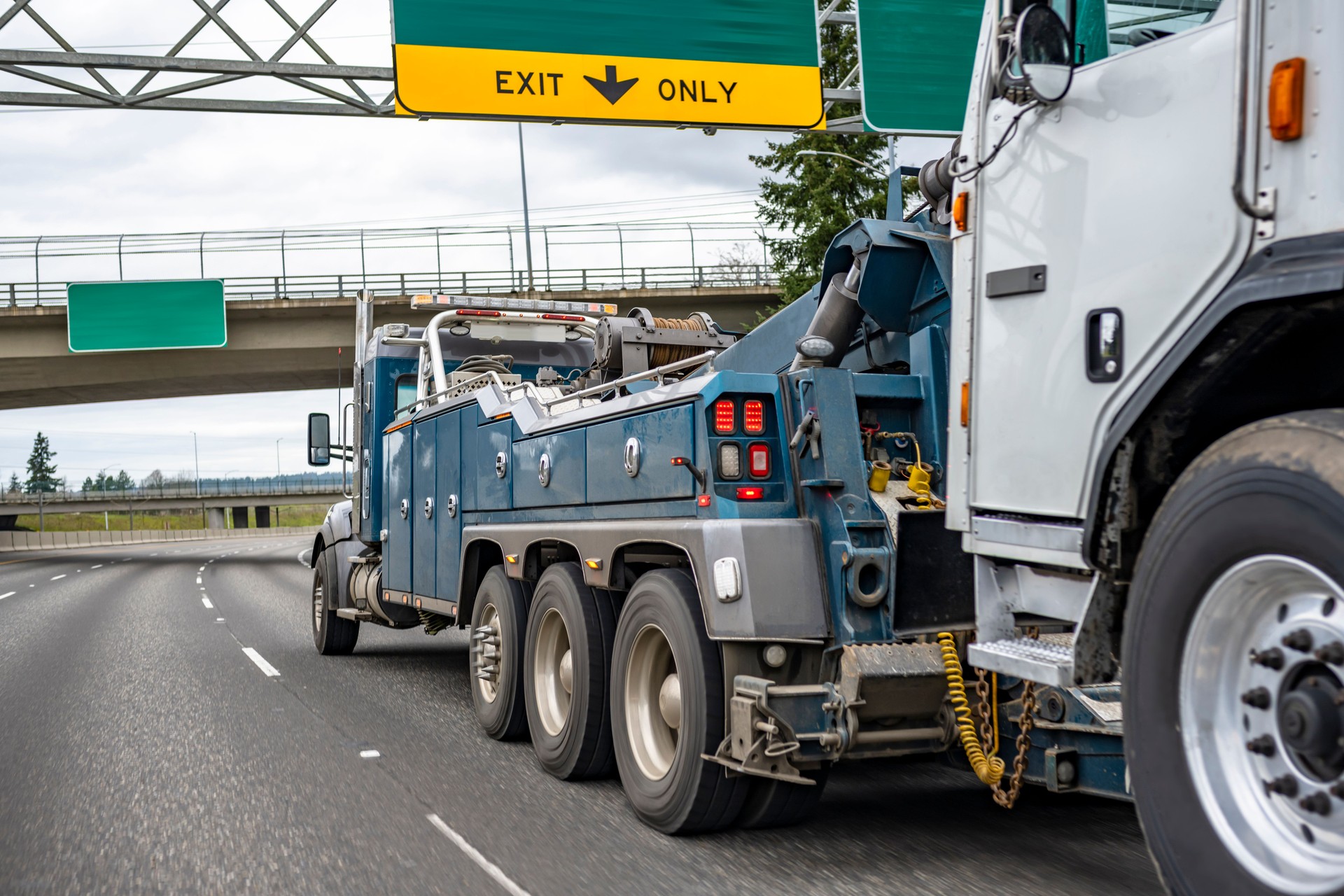 Broken white high cab big rig semi truck with open hood and loaded semi trailer on the road side shoulder waiting for mobile roadside assistance or towing truck for help
